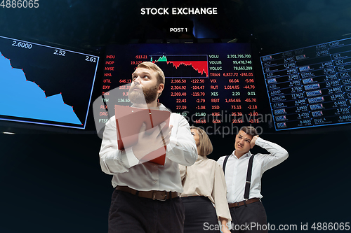 Image of Nervous tensioned investors analyzing crisis stock market with charts on screen on background, falling stock exchange