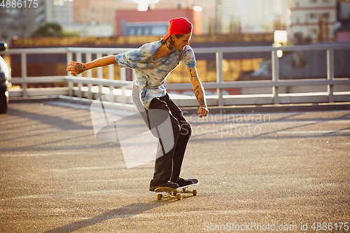 Image of Skateboarder doing a trick at the city\'s street in summer\'s sunshine