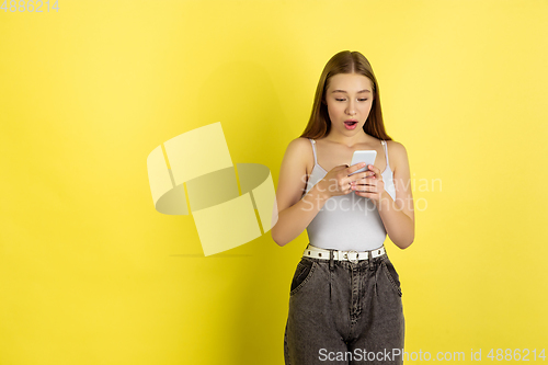 Image of Caucasian young girl\'s portrait isolated on yellow studio background. Beautiful female model. Concept of human emotions, facial expression, sales, ad, youth culture.