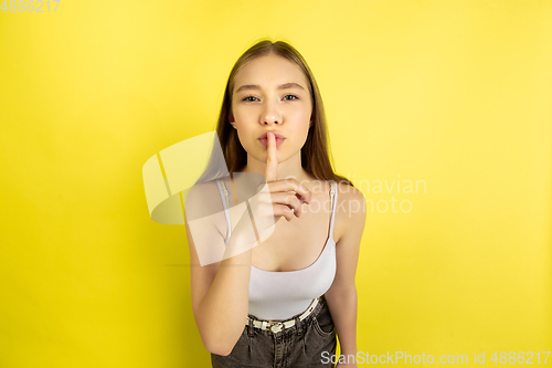 Image of Caucasian young girl\'s portrait isolated on yellow studio background. Beautiful female model. Concept of human emotions, facial expression, sales, ad, youth culture.