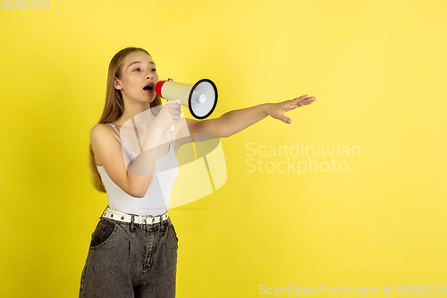 Image of Caucasian young girl\'s portrait isolated on yellow studio background. Beautiful female model. Concept of human emotions, facial expression, sales, ad, youth culture.