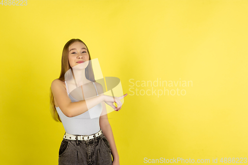 Image of Caucasian young girl\'s portrait isolated on yellow studio background. Beautiful female model. Concept of human emotions, facial expression, sales, ad, youth culture.