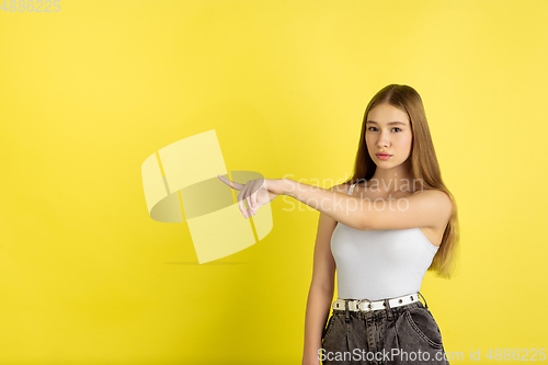 Image of Caucasian young girl\'s portrait isolated on yellow studio background. Beautiful female model. Concept of human emotions, facial expression, sales, ad, youth culture.