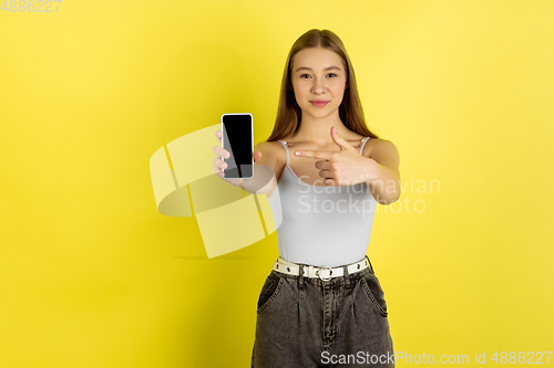 Image of Caucasian young girl\'s portrait isolated on yellow studio background. Beautiful female model. Concept of human emotions, facial expression, sales, ad, youth culture.