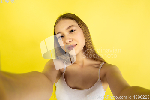 Image of Caucasian young girl\'s portrait isolated on yellow studio background. Beautiful female model. Concept of human emotions, facial expression, sales, ad, youth culture.