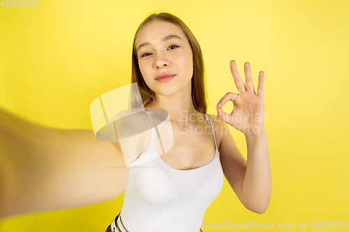 Image of Caucasian young girl\'s portrait isolated on yellow studio background. Beautiful female model. Concept of human emotions, facial expression, sales, ad, youth culture.