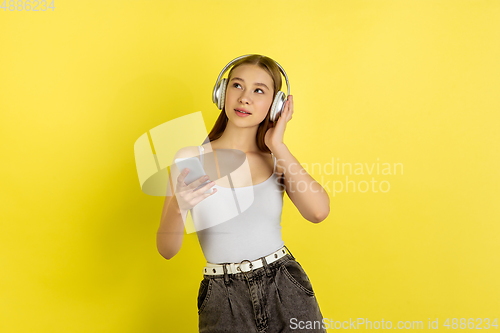 Image of Caucasian young girl\'s portrait isolated on yellow studio background. Beautiful female model. Concept of human emotions, facial expression, sales, ad, youth culture.