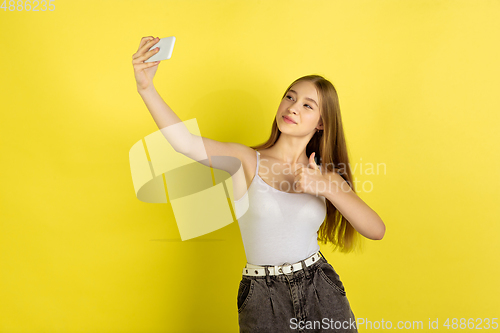 Image of Caucasian young girl\'s portrait isolated on yellow studio background. Beautiful female model. Concept of human emotions, facial expression, sales, ad, youth culture.