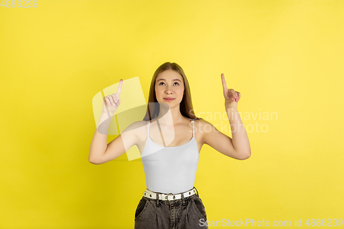 Image of Caucasian young girl\'s portrait isolated on yellow studio background. Beautiful female model. Concept of human emotions, facial expression, sales, ad, youth culture.