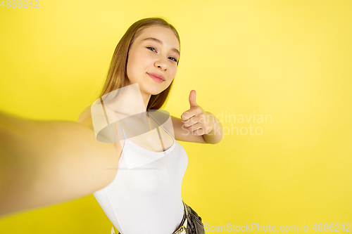 Image of Caucasian young girl\'s portrait isolated on yellow studio background. Beautiful female model. Concept of human emotions, facial expression, sales, ad, youth culture.