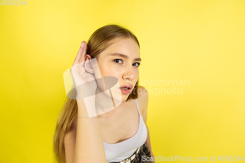 Image of Caucasian young girl\'s portrait isolated on yellow studio background. Beautiful female model. Concept of human emotions, facial expression, sales, ad, youth culture.