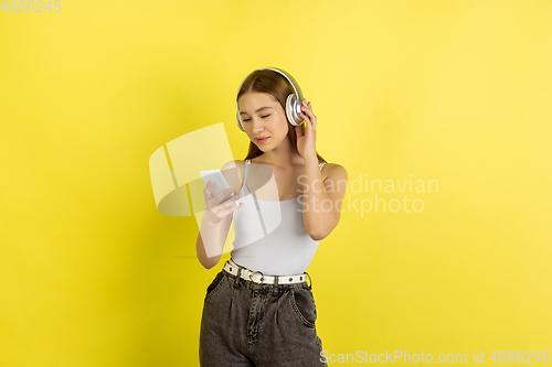 Image of Caucasian young girl\'s portrait isolated on yellow studio background. Beautiful female model. Concept of human emotions, facial expression, sales, ad, youth culture.