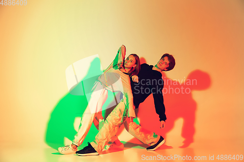 Image of Young man and woman dancing hip-hop, street style isolated on studio background in neon light