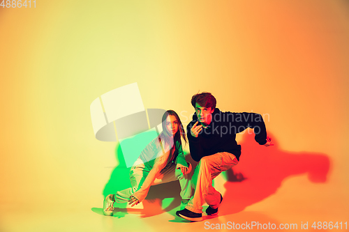 Image of Young man and woman dancing hip-hop, street style isolated on studio background in neon light