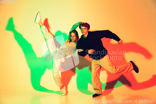 Image of Young man and woman dancing hip-hop, street style isolated on studio background in neon light