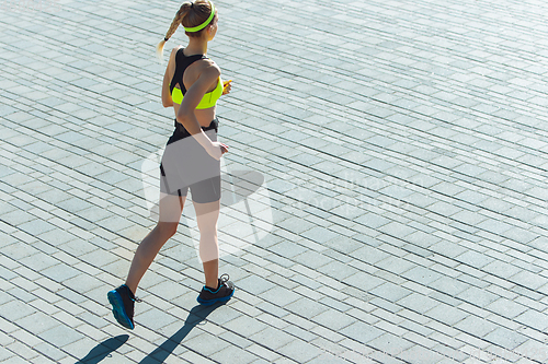 Image of Female runner, athlete training outdoors in summer\'s sunny day.