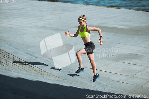 Image of Female runner, athlete training outdoors in summer\'s sunny day.