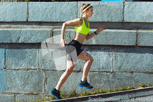 Image of Female runner, athlete training outdoors in summer\'s sunny day.