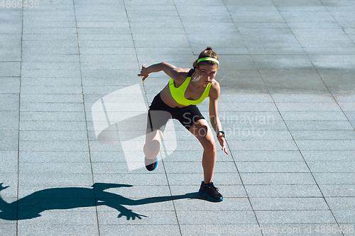 Image of Female runner, athlete training outdoors in summer\'s sunny day.