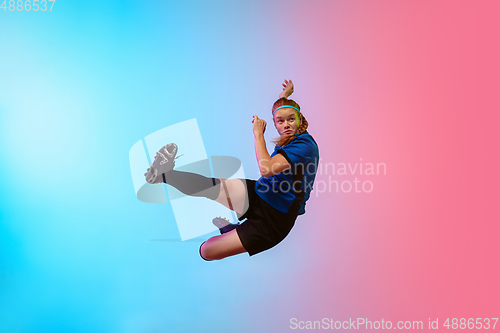 Image of Female soccer, football player training in action isolated on gradient studio background in neon light