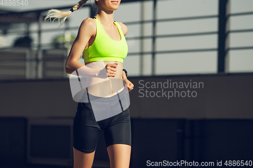 Image of Female runner, athlete training outdoors in summer\'s sunny day.