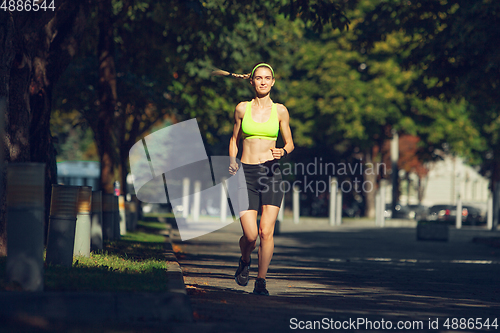 Image of Female runner, athlete training outdoors in summer\'s sunny day.