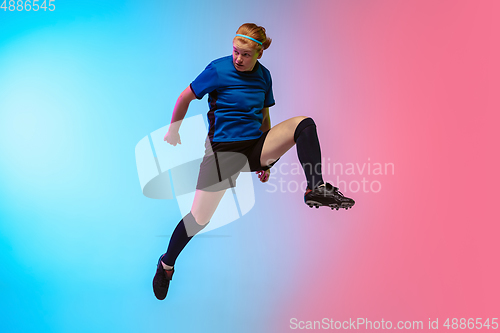 Image of Female soccer, football player training in action isolated on gradient studio background in neon light