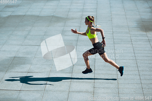 Image of Female runner, athlete training outdoors in summer\'s sunny day.