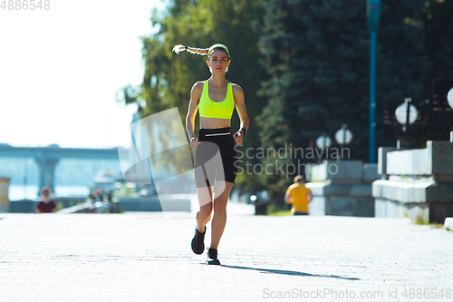 Image of Female runner, athlete training outdoors in summer\'s sunny day.