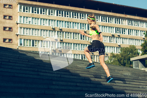 Image of Female runner, athlete training outdoors in summer\'s sunny day.