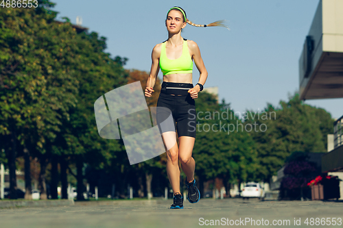 Image of Female runner, athlete training outdoors in summer\'s sunny day.