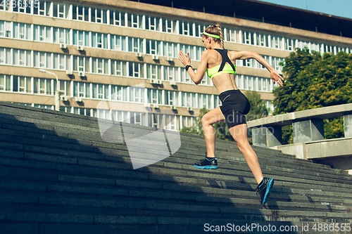 Image of Female runner, athlete training outdoors in summer\'s sunny day.