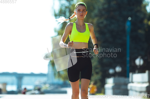 Image of Female runner, athlete training outdoors in summer\'s sunny day.