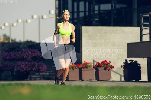 Image of Female runner, athlete training outdoors in summer\'s sunny day.