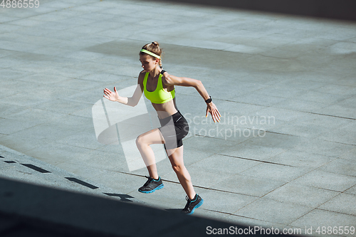 Image of Female runner, athlete training outdoors in summer\'s sunny day.