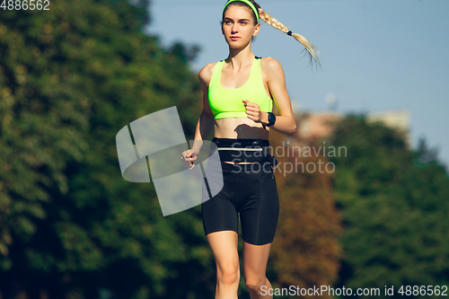 Image of Female runner, athlete training outdoors in summer\'s sunny day.