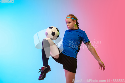 Image of Female soccer, football player training in action isolated on gradient studio background in neon light