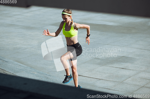 Image of Female runner, athlete training outdoors in summer\'s sunny day.