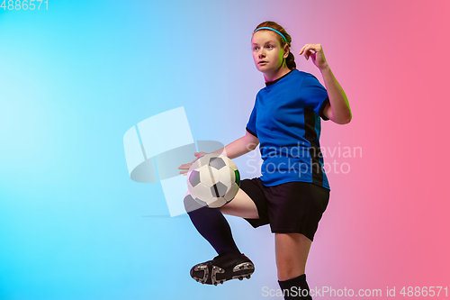 Image of Female soccer, football player training in action isolated on gradient studio background in neon light