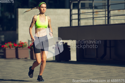 Image of Female runner, athlete training outdoors in summer\'s sunny day.