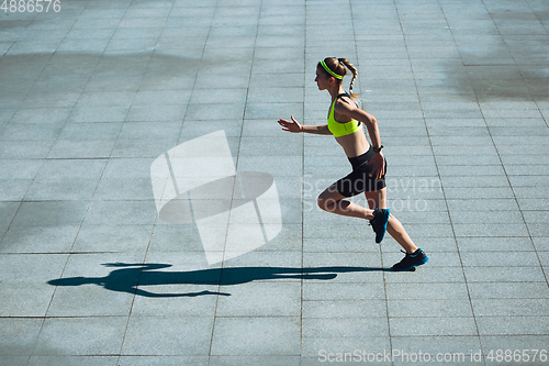 Image of Female runner, athlete training outdoors in summer\'s sunny day.