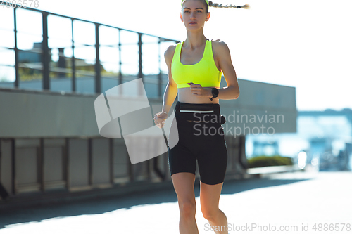 Image of Female runner, athlete training outdoors in summer\'s sunny day.