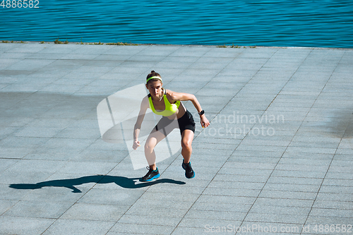 Image of Female runner, athlete training outdoors in summer\'s sunny day.