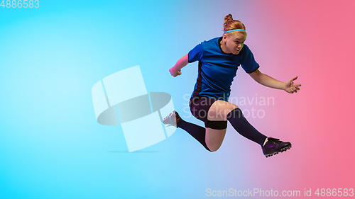 Image of Female soccer, football player training in action isolated on gradient studio background in neon light