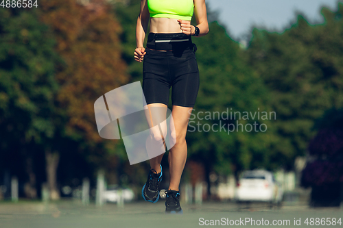 Image of Female runner, athlete training outdoors in summer\'s sunny day.