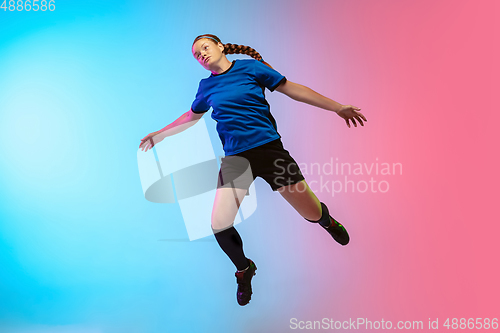 Image of Female soccer, football player training in action isolated on gradient studio background in neon light