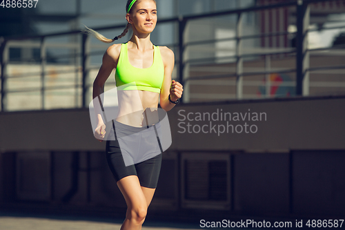 Image of Female runner, athlete training outdoors in summer\'s sunny day.