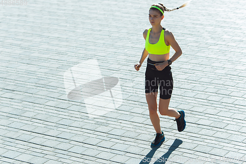 Image of Female runner, athlete training outdoors in summer\'s sunny day.