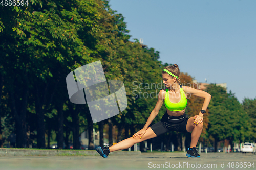 Image of Female runner, athlete training outdoors in summer\'s sunny day.