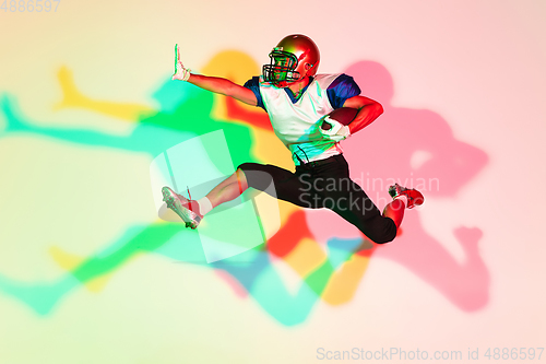 Image of American football player isolated on gradient studio background in neon light with shadows